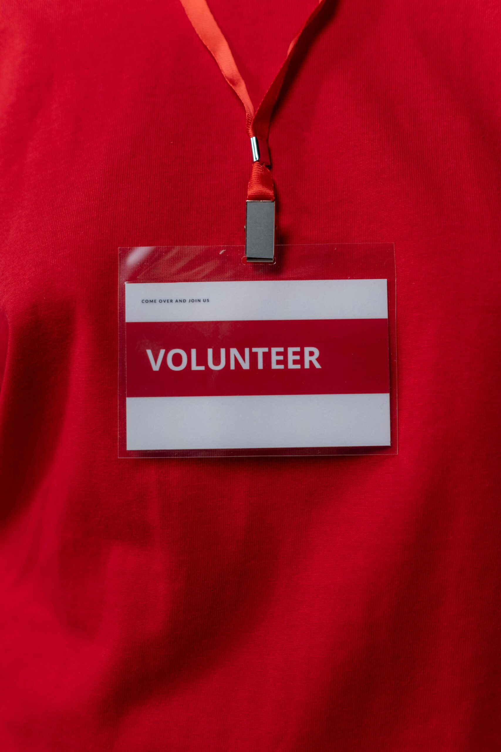 A close-up of a volunteer name tag hanging on a red lanyard, symbolizing community service.